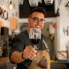 Sommelier chileno ofreciendo una copa de vino tinto en un restaurante moderno, representando el servicio de vinos profesional.