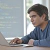 Programación orientada a objetos en desarrollo web: estudiante programando una aplicación básica en laptop.