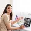 Mujer profesional sonriendo mientras estudia inglés online con la plataforma Speexx en su laptop.