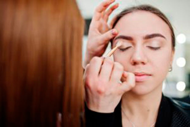 Persona recibiendo una clase de maquillaje, aplicando sombras en los ojos como parte del curso online de visagismo y automaquillaje.