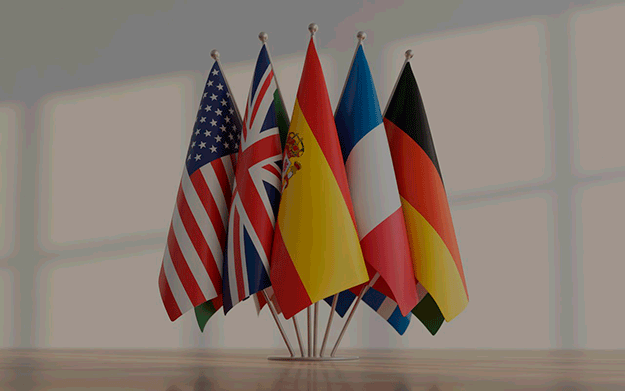 Banderas de distintos países en soporte metálico sobre fondo claro que representan el aprendizaje de idiomas y la comunicación global.